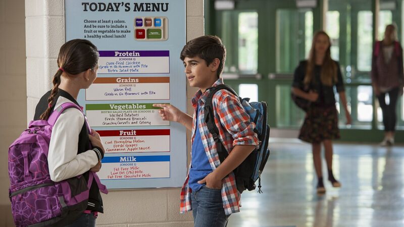 Two students reading the school lunch menu board outside the cafeteria